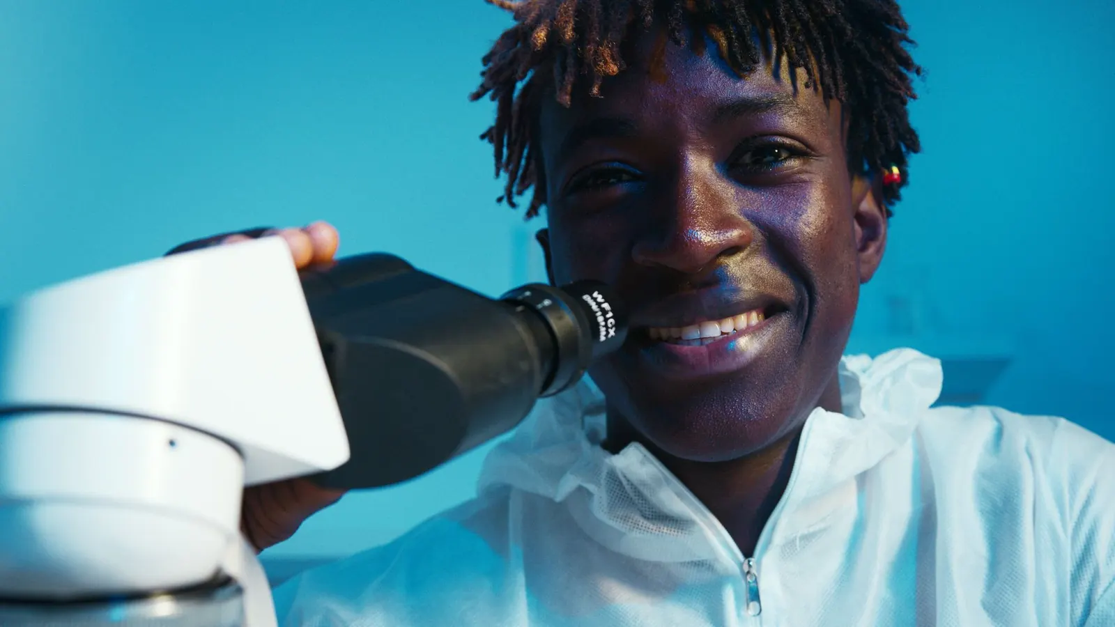 Smiling laboratory scientist looking into a microscope